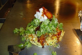 Picture of freshly prepared Hiroshima style okonomiyaki on a hibachi style grill in the Seibu region